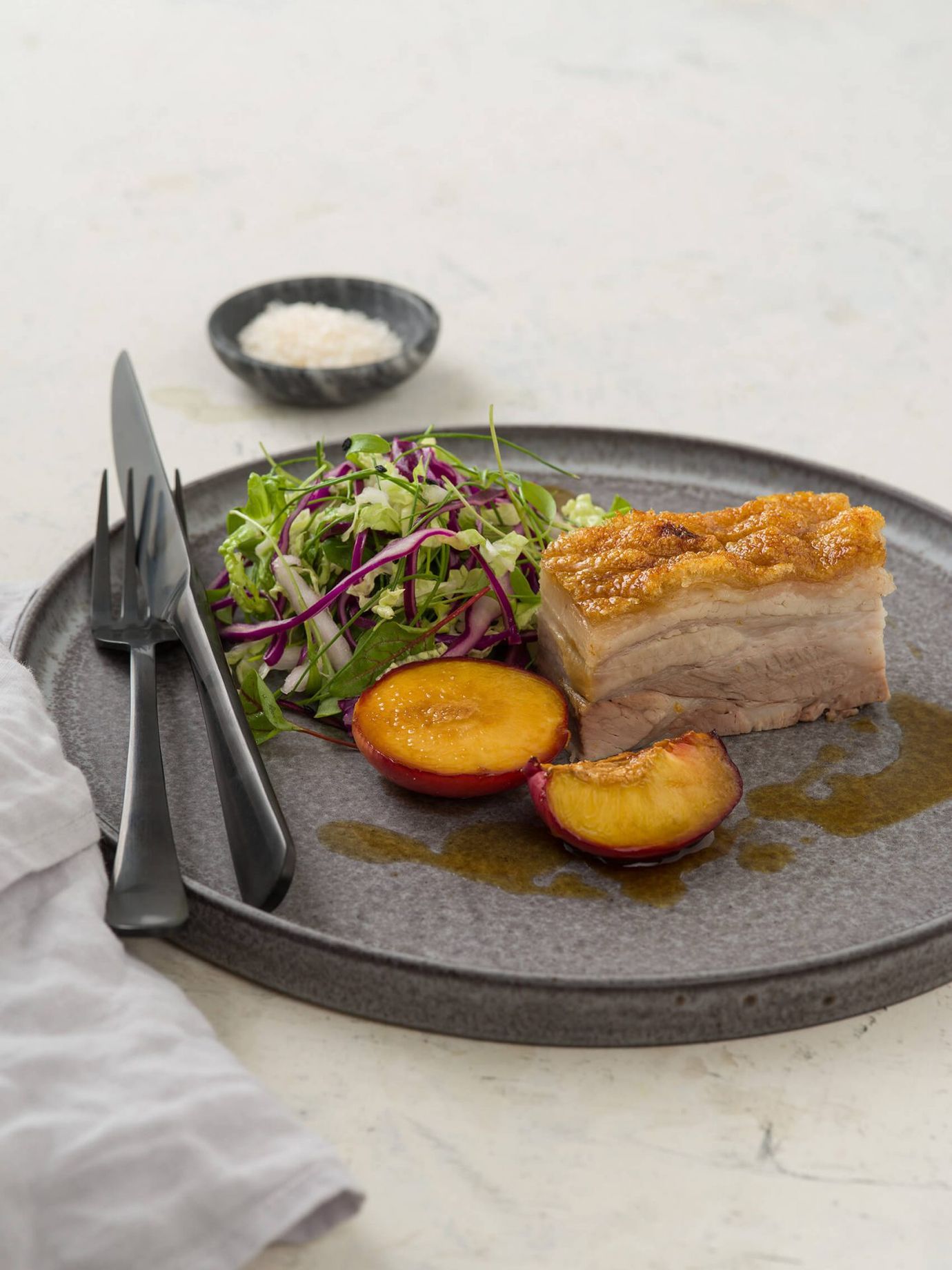 Pressed pork belly with grilled plums and masterstock reduction, served with easy summer slaw