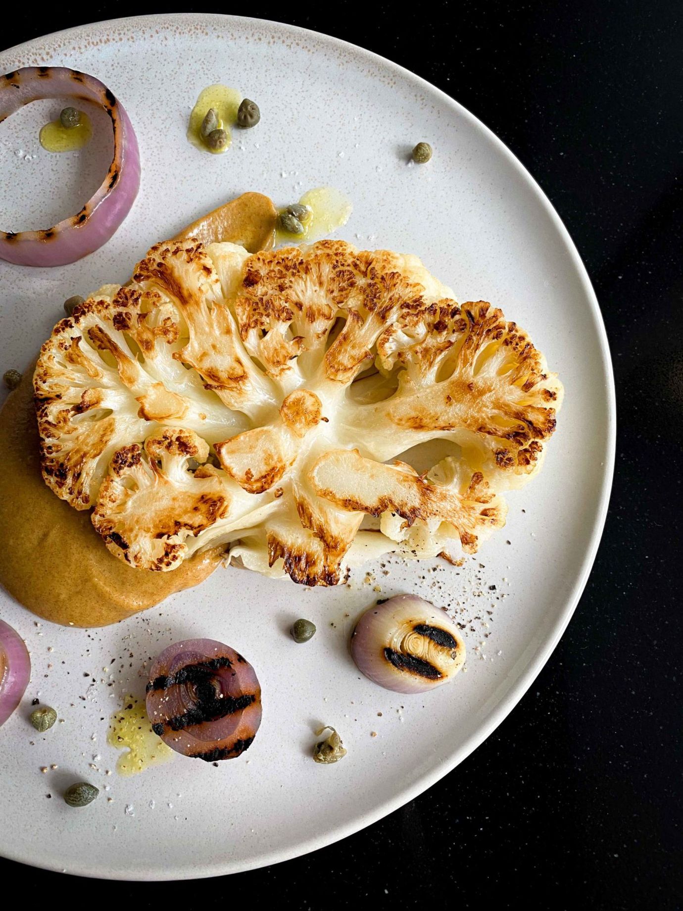 Cauliflower steaks with date sauce, charred onions and capers