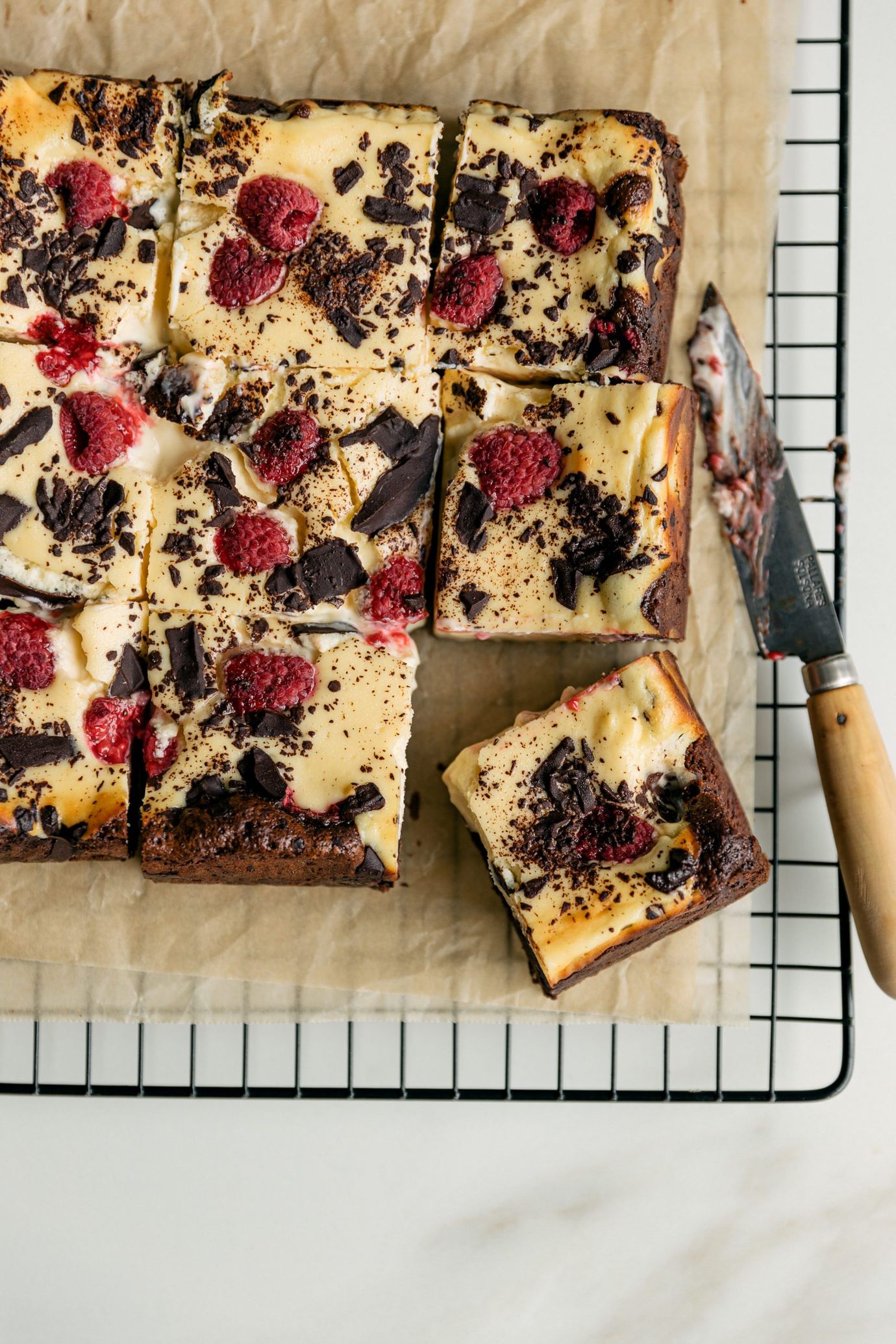 Chocolate brownie cheesecake bars with fresh raspberries and dark chocolate