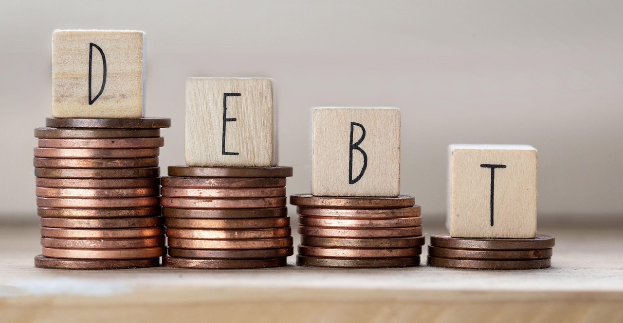 Debt written on wooden cubes with letters on piles of coins Debt written on wooden cubes with letters on piles of coins