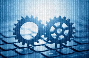 Two gears on computer keyboard with computer code in the background