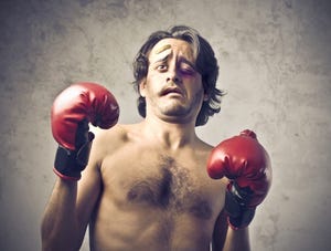 shirtless man with bruised face and boxing gloves