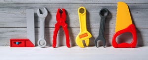 Set of plastic toy tools for children in a line on a wooden background