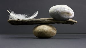 rock and feather balanced on another rock