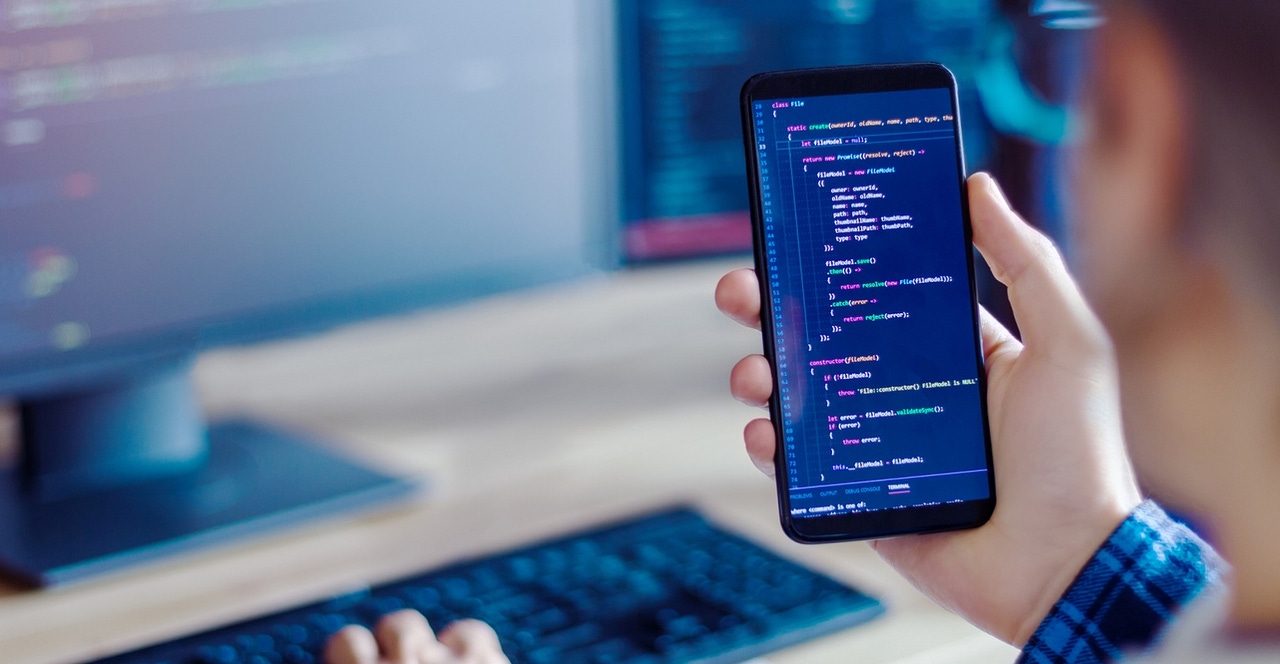 man developing code on laptop and phone man developing code on laptop and phone