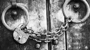 black and white image of wooden door with chain and padlock on its handles