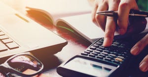 person using calculator next to a laptop person using calculator next to a laptop