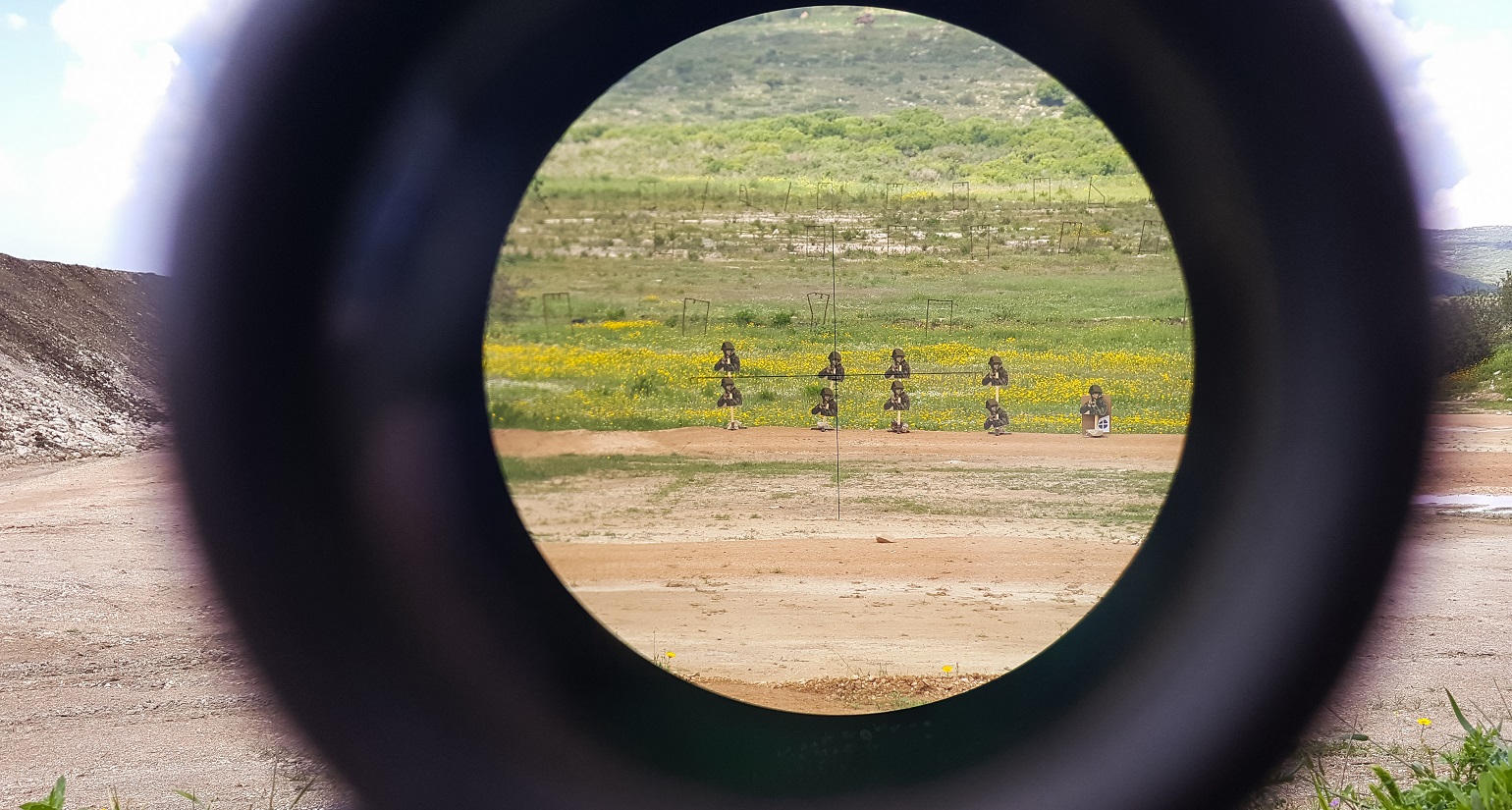 A look through an optical sight aimed at a group of potential targets at the range