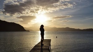 Person standing at end of dock close to sunset