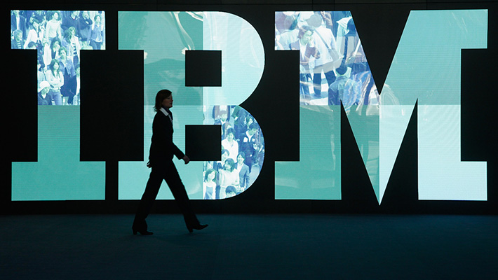 A person walks in front of an IBM logo.