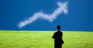businessman standing in a field looking at a cloud shaped like an arrow