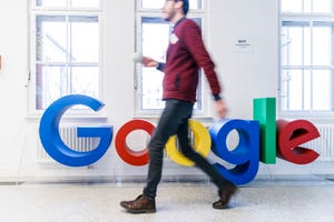 man walking past google logo