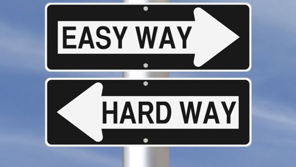two black and white road signs pointing opposite reading EASY WAY and HARD WAY