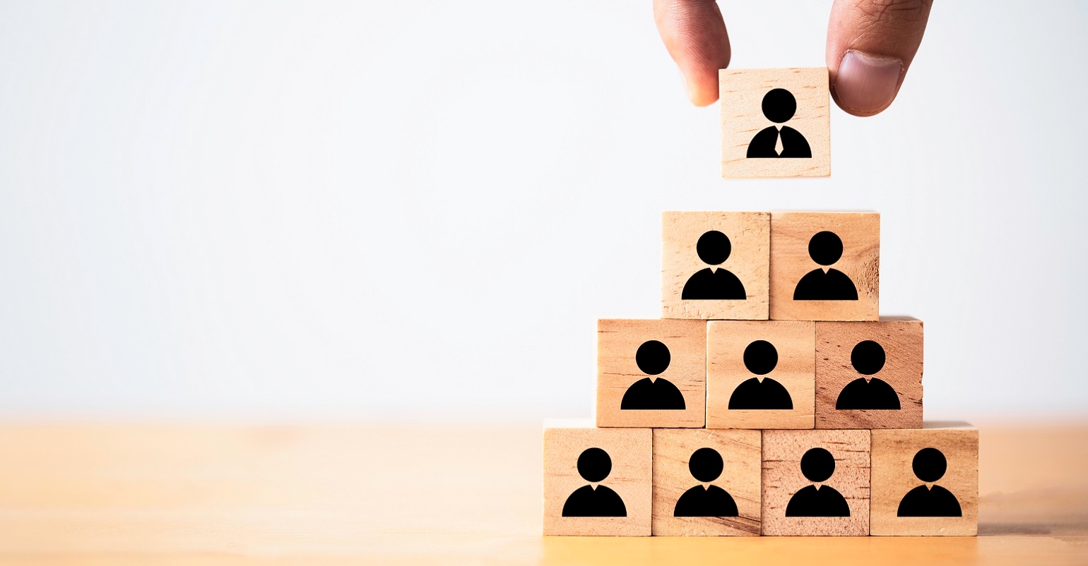 Hand putting manager icon on top of wooden stacking of staff icons