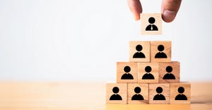 Hand putting manager icon on top of wooden stacking of staff icons Hand putting manager icon on top of wooden stacking of staff icons