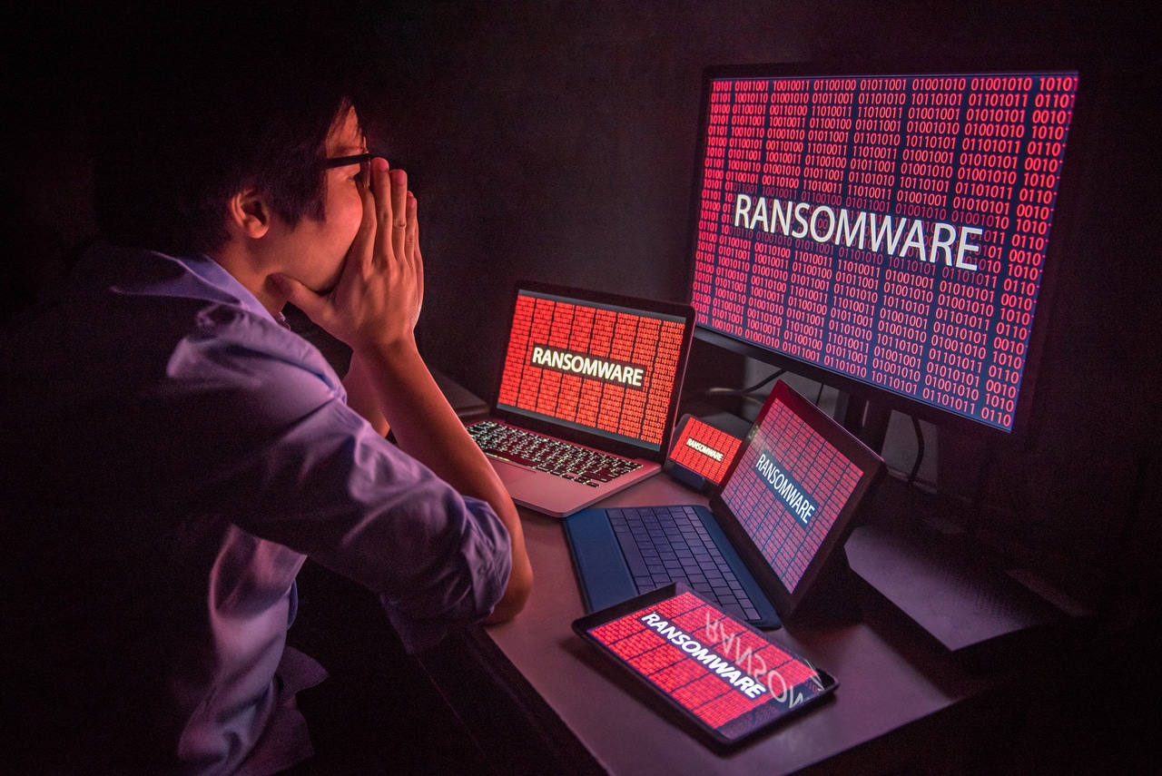 an upset worker looks at computers with a ransomware message on the screens an upset worker looks at computers with a ransomware message on the screens