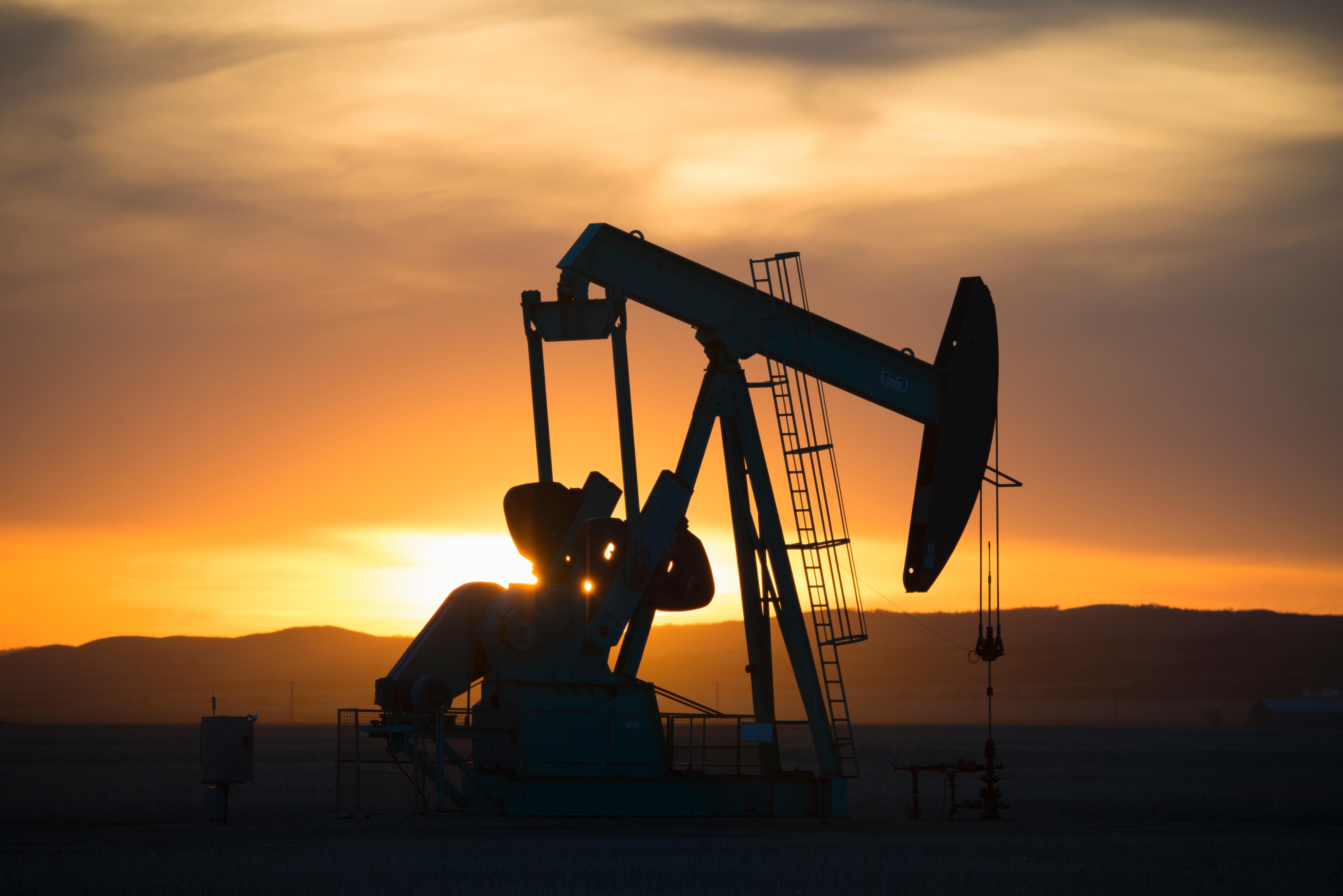 A pumpjack at an oil drilling site at sunset