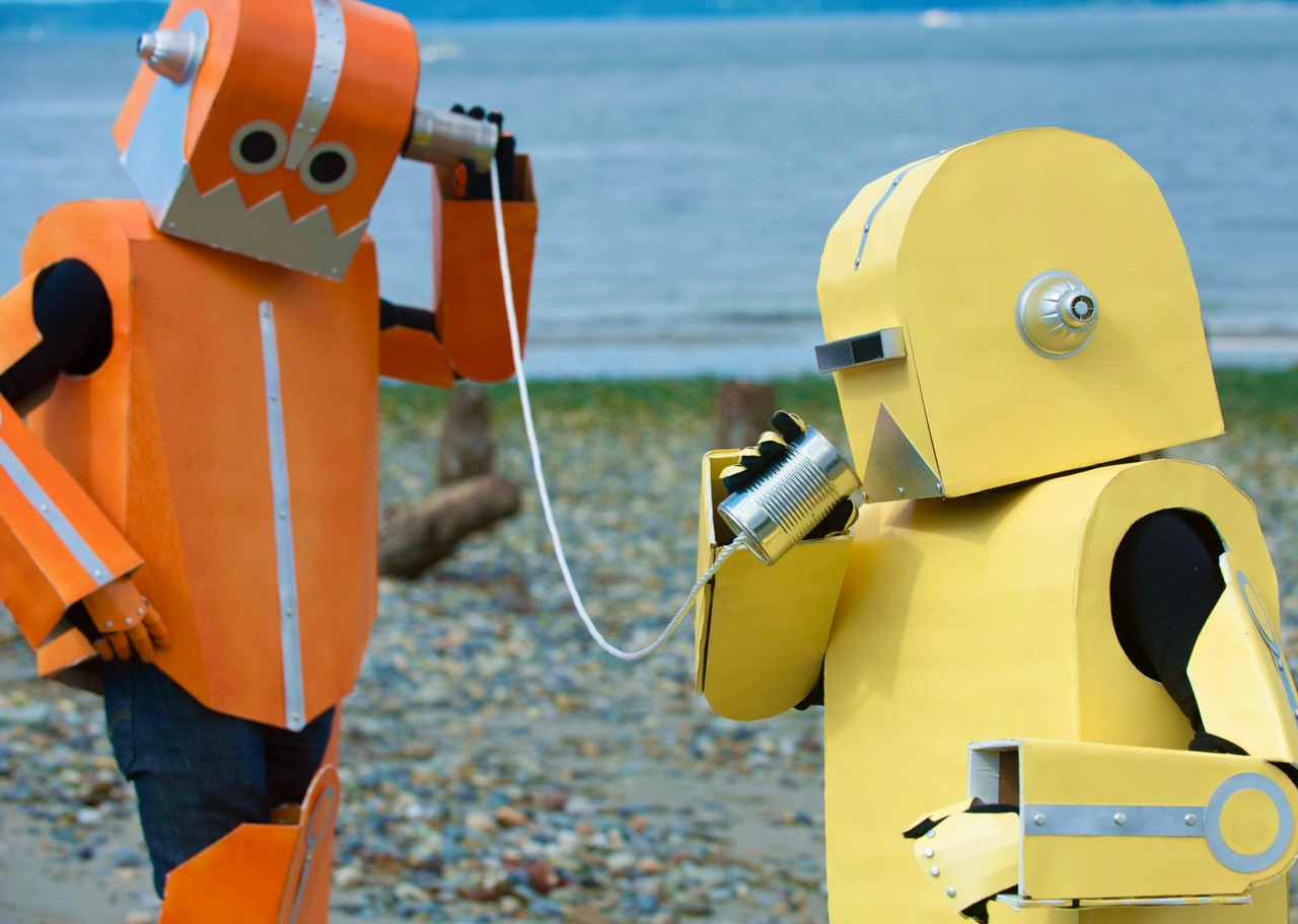 two colorful robots communicating, conversing with each other through tin can telephone two colorful robots communicating, conversing with each other through tin can telephone