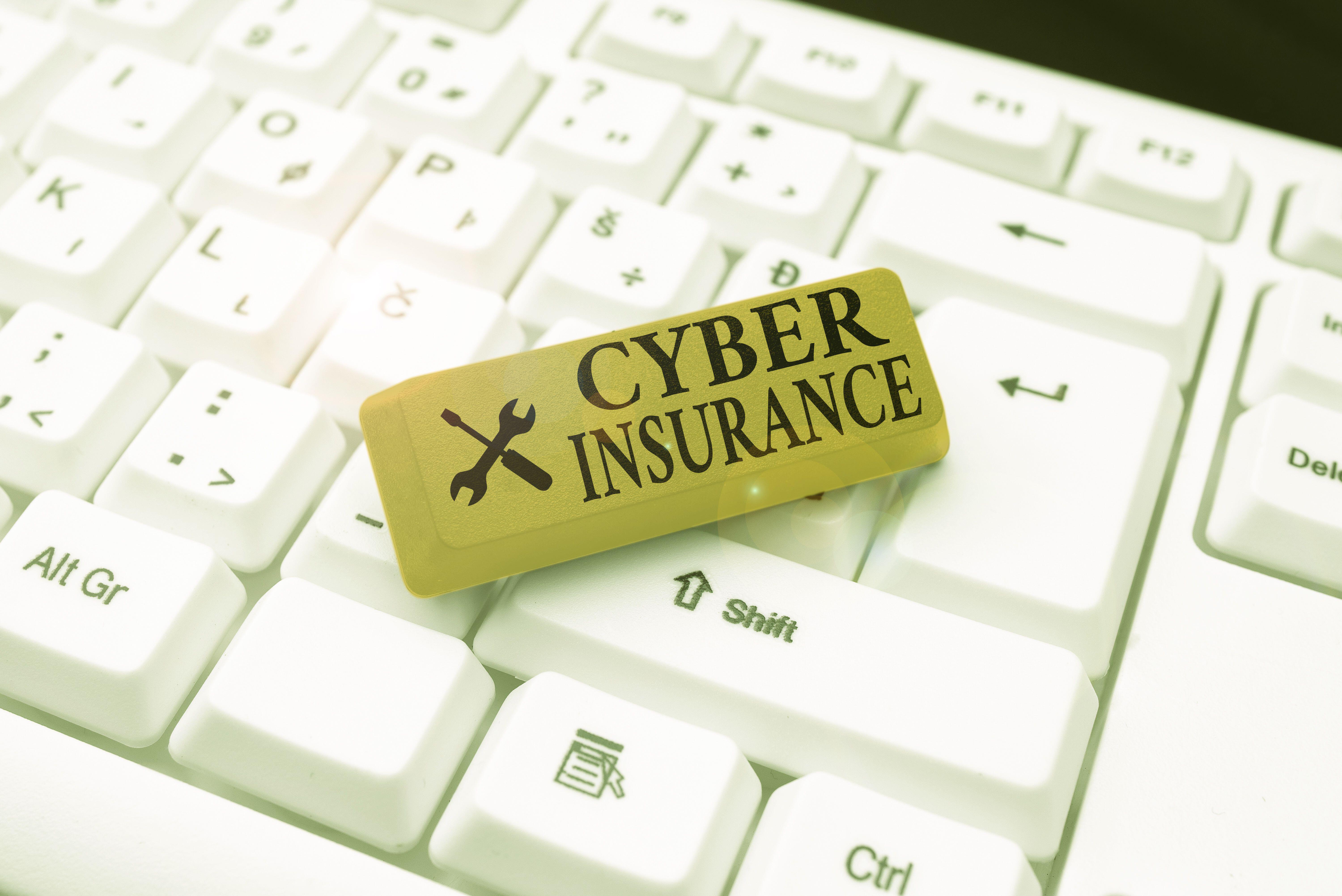Photo of a keyboard with a yellow key labeled with "cyber insurance" text.
