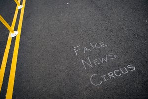 asphalt road with the words Fake News Circus written in chalk