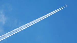 Plane flying across blue sky with cloud trail