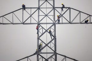 Technicians work on an unconnected transmission tower