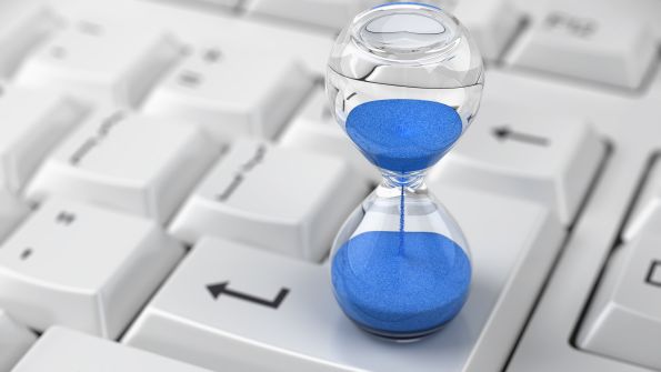 hourglass with blue sand on a computer keyboard hourglass with blue sand on a computer keyboard