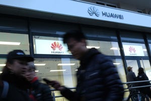 People walk past a Huawei store