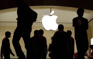 People are silhouetted against a bright Apple Store logo People are silhouetted against a bright Apple Store logo