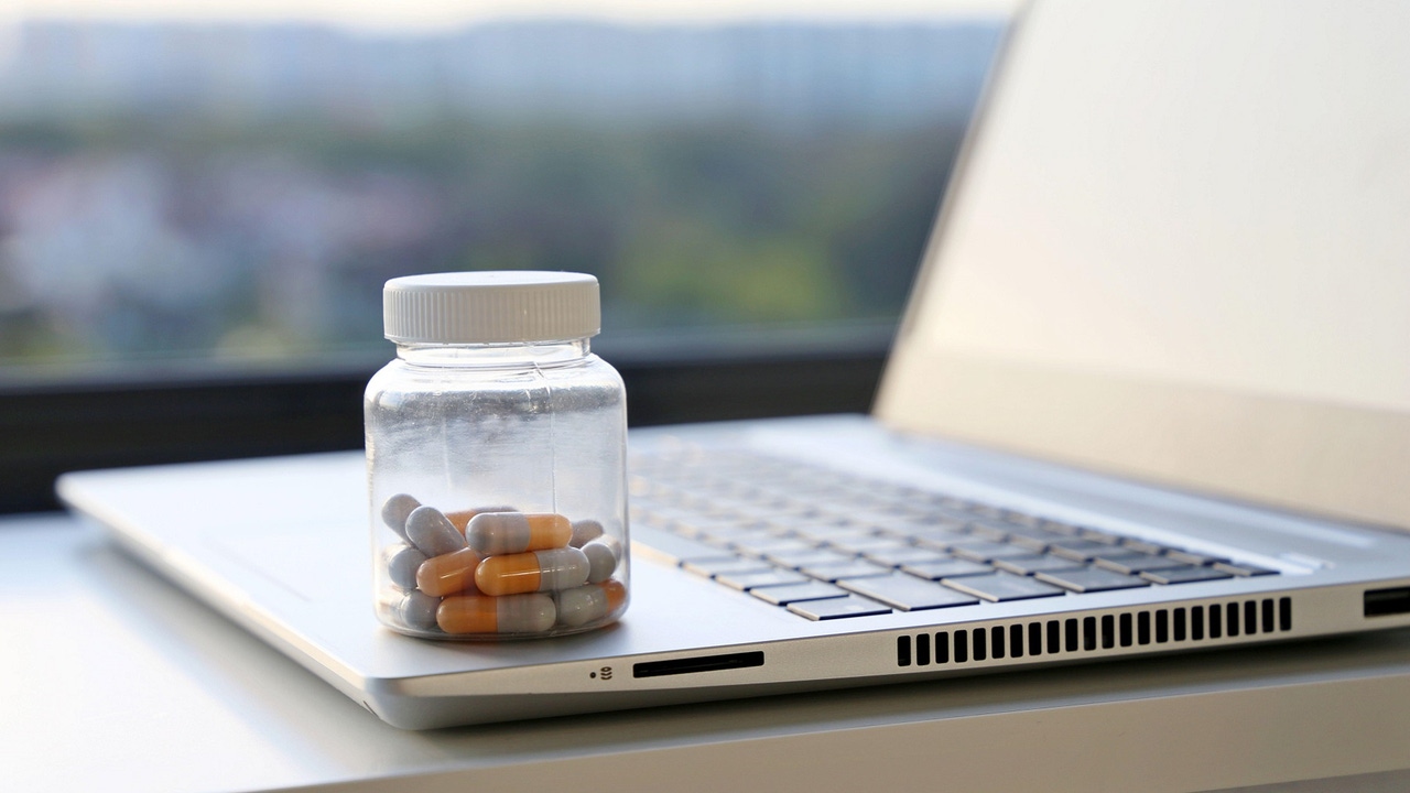 bottle of pills sitting on a laptop bottle of pills sitting on a laptop