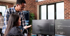 Diverse team of software programmers using computers and writing code while collaborating on project