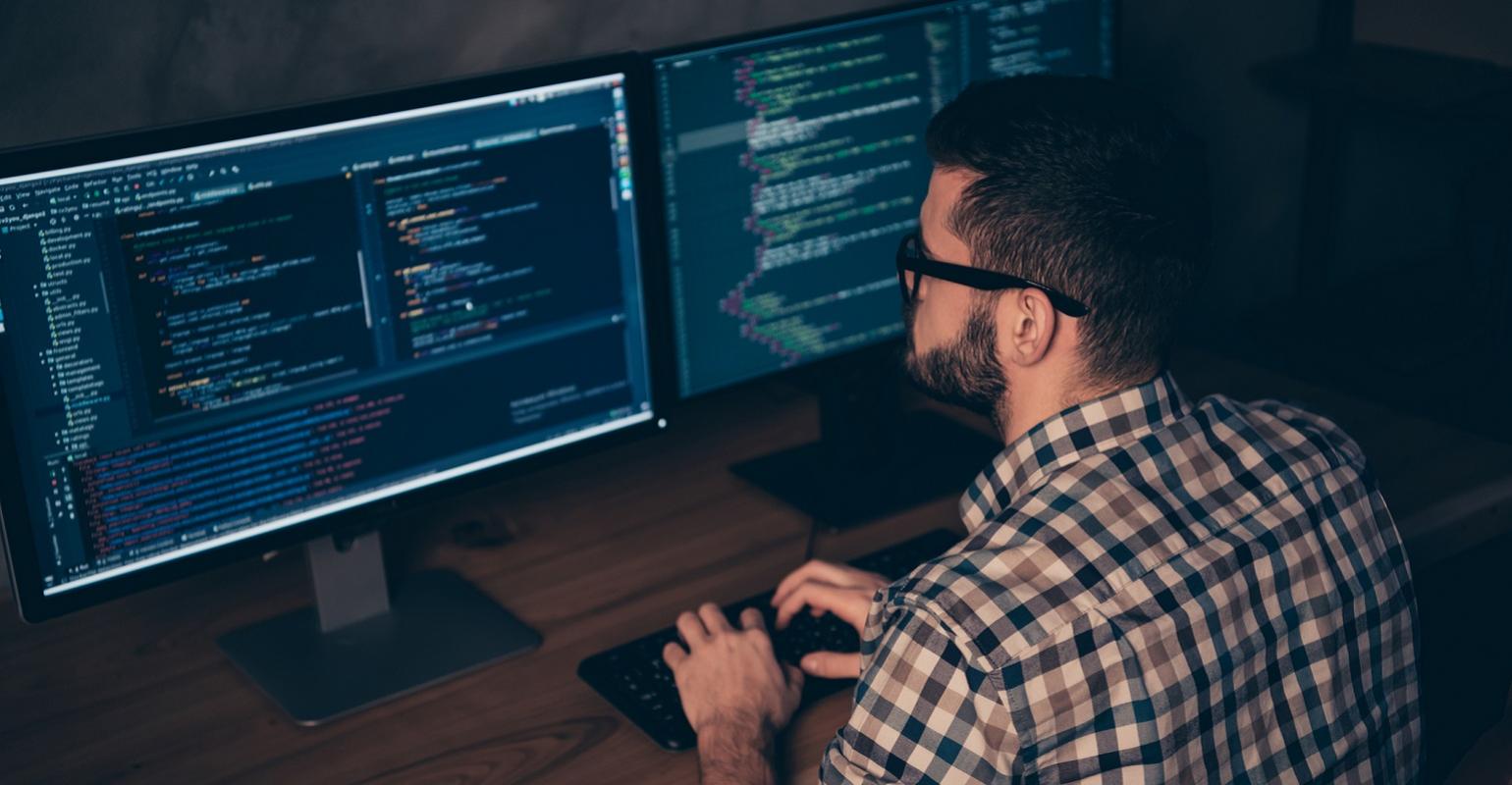 developer writing code on multiple screens
