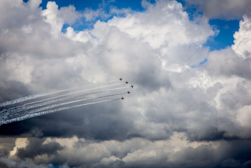 Fighter planes are backlit against the clouds