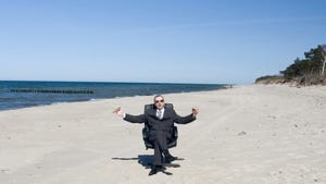 guy in business suit sitting in desk chair on a beach