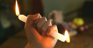 Person holding candle burning at both ends