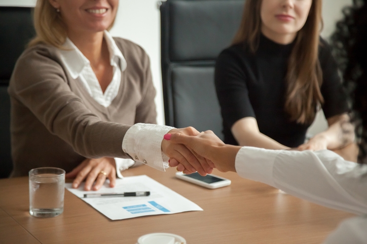 Two business people sit at a table with paper work