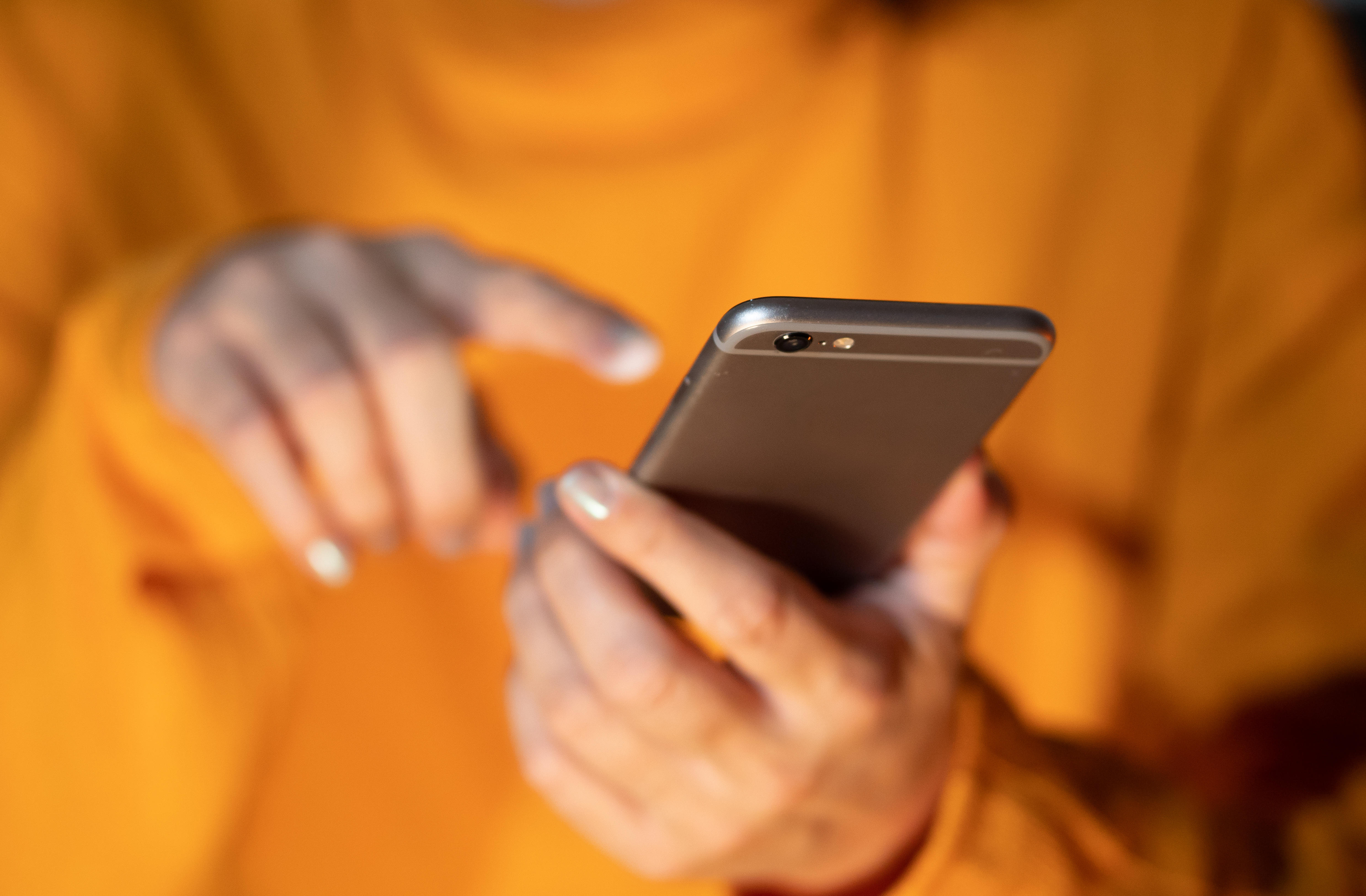 Person in orange shirt holding mobile phone