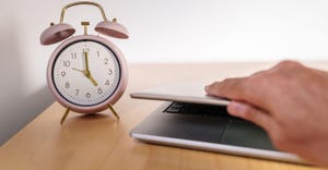 alarm clock strikes 5 and employee closes laptop