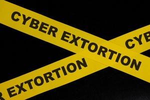 Yellow barricade tape with the words cyber extortion Yellow barricade tape with the words cyber extortion
