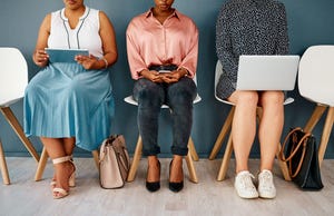 Studio shot of a group of unrecognizable businesswomen using wireless technology while sitting in line against.