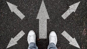 person standing on a road with multiple arrows pointing in different directions