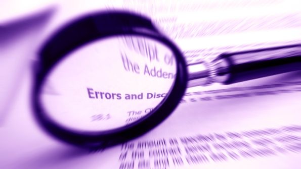magnifying glass sitting on papers magnifying the word ERRORS magnifying glass sitting on papers magnifying the word ERRORS