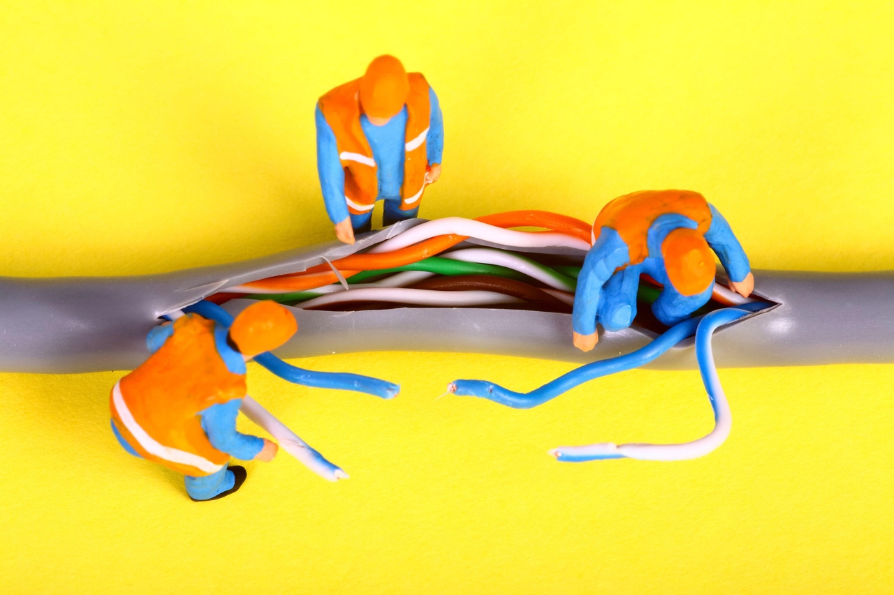 miniature toy workers in orange vests investigating a fault on a broadband network cable miniature toy workers in orange vests investigating a fault on a broadband network cable