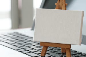 blank canvas and wooden easel on laptop computer