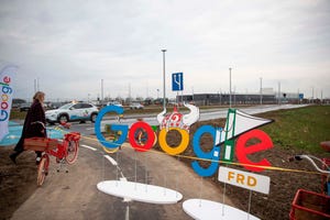 A woman passes by a Google themed barrier in front of a Google data center in Fredericia, Denmark (November 2020)