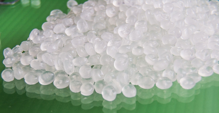 Stock image of clear plastic pellets on green background