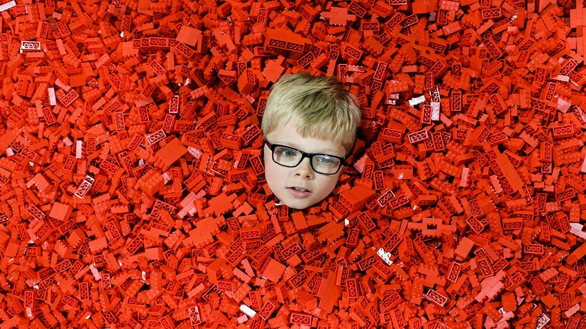 Child's head poking out of Lego pit.