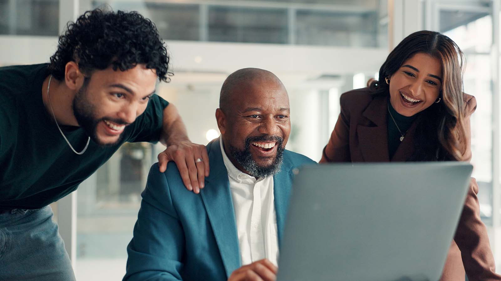 Happy businessman and staff looking at laptop