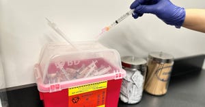used medical syringe being put in red container