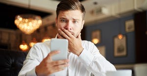 Businessman checking mobile phone with puzzled look